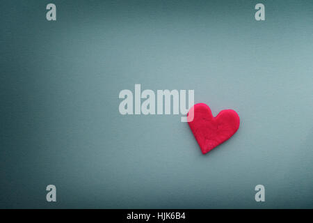 Red heart with small cracks on blue background. Close up. Stock Photo
