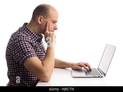 thoughtful man working on his laptop computer. Side view Stock Photo