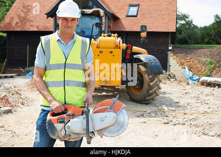 Construction Worker On Site Holding Circular Saw Stock Photo