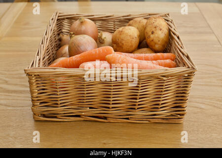 Basket of vegetables carrots onions potatoes on a wooden table Stock Photo