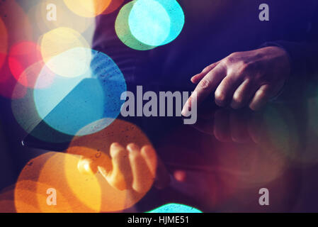 Close up of female hands using digital tablet computer, abstract low key composition with colorful bokeh light Stock Photo