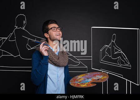Inspired handsome man holding palette and painting. Stock Photo