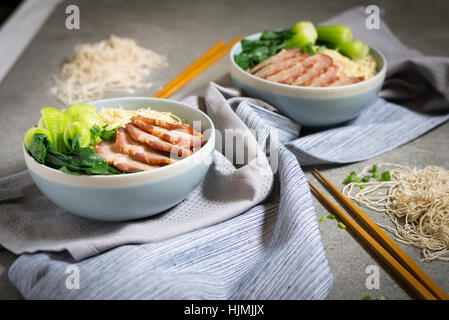 delicious egg noodle with red pork and vegetable in bowl decoration with chopstick on table,thaifood,selective focus. Stock Photo