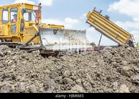 View on heavy bulldozer while he moving, leveling ground at construction site.  Heavy wheels are working at construction site. Stock Photo
