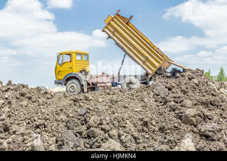 View on heavy bulldozer while he moving, leveling ground at construction site.  Heavy wheels are working at construction site. Stock Photo