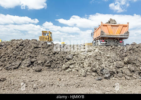 View on heavy bulldozer while he moving, leveling ground at construction site.  Heavy wheels are working at construction site. Stock Photo