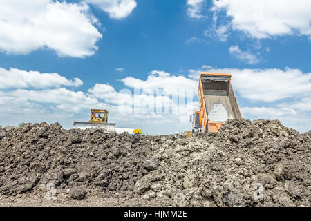 View on heavy bulldozer while he moving, leveling ground at construction site.  Heavy wheels are working at construction site. Stock Photo