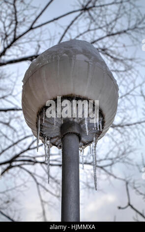 Frozen street light with icicles in cold winter day closeup Stock Photo