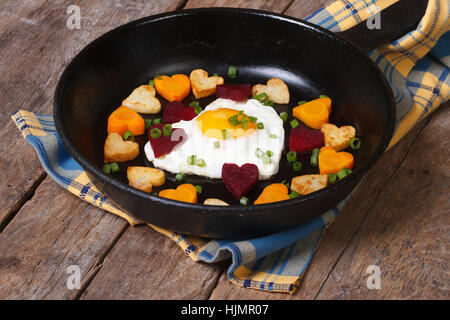 Fried egg in form heart on pan and little hearts, carrots, beets and potatoes Stock Photo