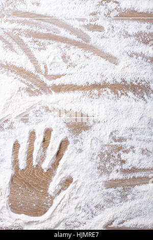 female palm print on flour scattered on the kitchen board. vertical background closeup Stock Photo