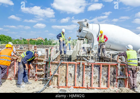 Zrenjanin, Vojvodina, Serbia - May 29, 2015: Workers at building site are pouring concrete in mold from mixer truck. Stock Photo