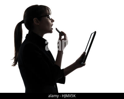 one business woman computer computing digital tablet apply g lipstick  silhouette studio isolated on white background Stock Photo