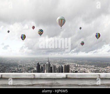 Colorful aerostats flying in clear sky above modern city Stock Photo ...