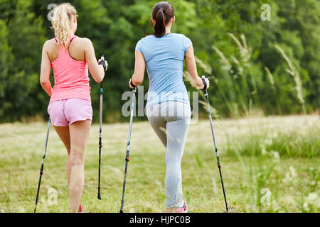 Two young women nordic walking together in the nature Stock Photo