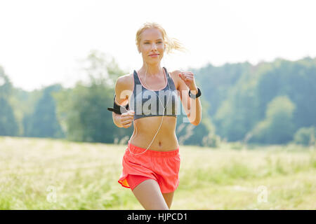 Young woman as jogger with mp3 player listens to music while running