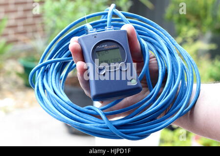 Hand holding Fluke Networks LinkRunner device with blue cabling Stock Photo
