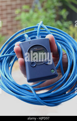 Hand holding Fluke Networks LinkRunner device with blue cabling Stock Photo