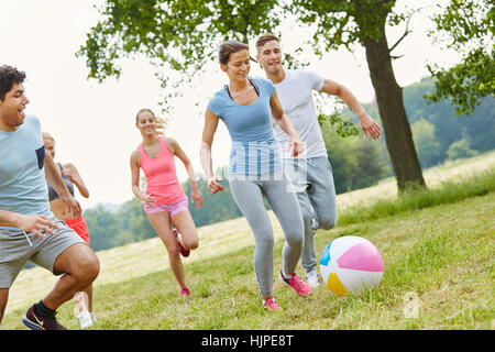 Friends playing with ball in movement having fun and being active Stock Photo