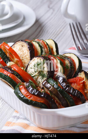 Baked vegetables tomatoes, zucchini and eggplant with cheese in baking dish close up on the table. vertical Stock Photo