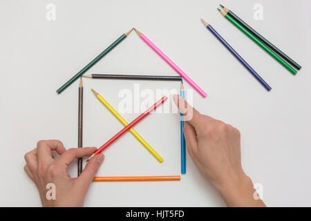Female hands corrected pencils, making one wooden house Stock Photo