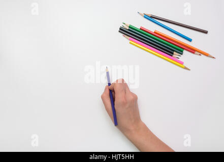 Woman's hand draws a pencil on paper, close-up, top view Stock Photo