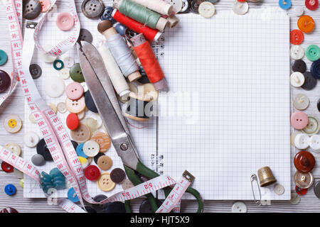 Background of sewing: scissors, thread, needles, measuring tape and notebook close up top view Stock Photo