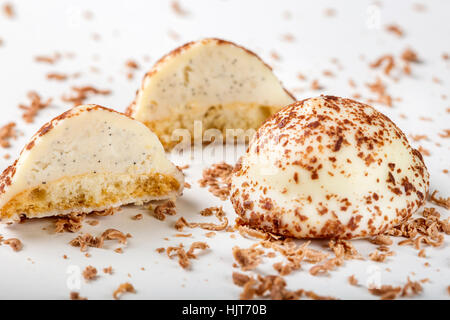 Two vanilla pearl candy, one cut in half, and grated dark chocolate on white background Stock Photo