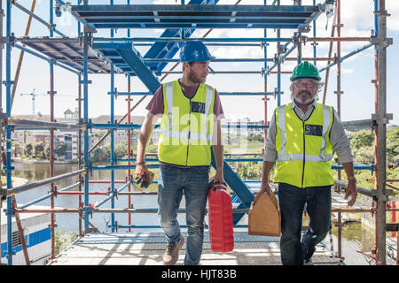 Construction workers on construction site carrying tool boxes Stock Photo