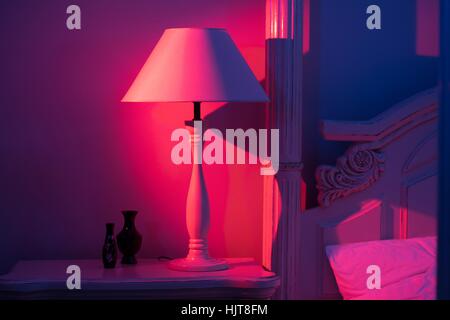 Luxurious minimalistic art décor Bedroom with royal bed, pink and blue light with stylish night lamp at the wooden table Stock Photo
