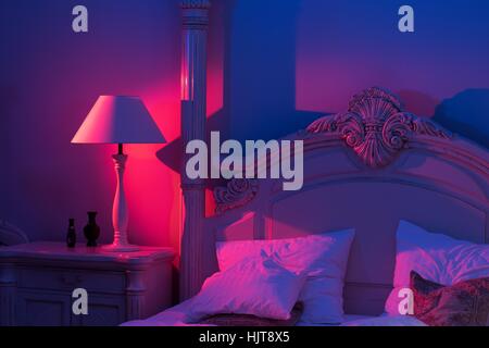 Luxurious minimalistic art décor Bedroom with royal bed, pink and blue light with stylish night lamp at the wooden table Stock Photo