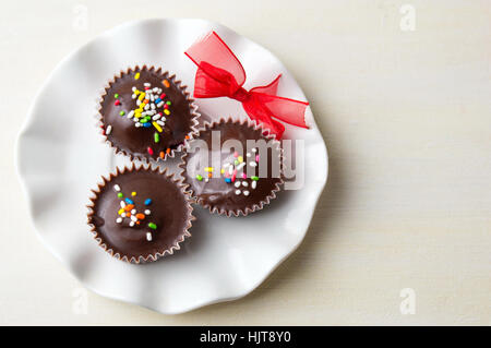 chocolate candies with colorful sprinkles on a white plate Stock Photo