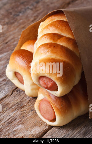 rolls with sausage closeup wrapped in paper on wooden background vertical