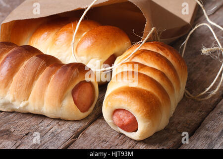 rolls with sausage closeup unpacked paper on wooden table horizontal