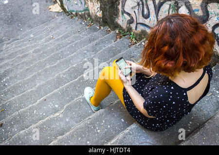 Above view of young caucasian female with short red hair looking at her phone Stock Photo