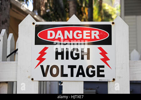 Danger High Voltage sign on white picket fence Stock Photo