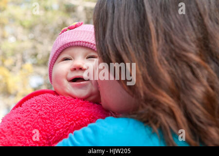 Cute smiling baby receiving a kiss from her mom Stock Photo