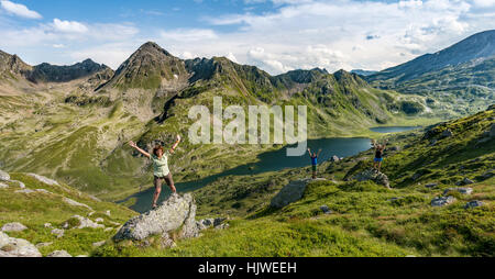 Three hikers standing on rocks in front of mountain landscape, Low Giglachsee, Rohrmoos-Obertal, Schladminger Tauern, Schladming Stock Photo