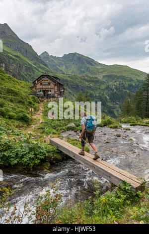 Hiker crosses wooden bridge across mountain stream, Golling Hut, Rohrmoos-Untertal, Schladming Tauern, Styria, Austria Stock Photo