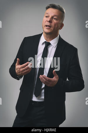 Senior Businessman Speaking and Gesturing. Gray background Stock Photo