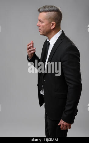 Senior Businessman Speaking and Gesturing. Gray background Stock Photo
