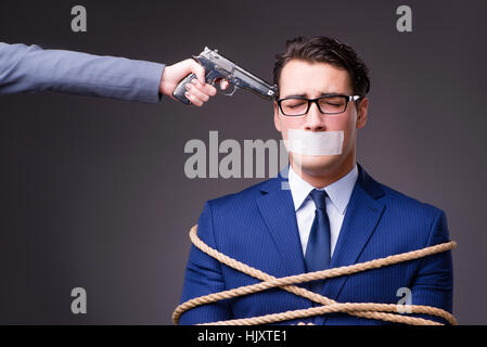 Businessman taken hostage and tied up with rope Stock Photo