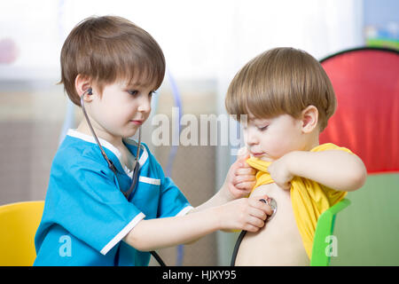 Children playing doctor in playroom or kindergarten Stock Photo