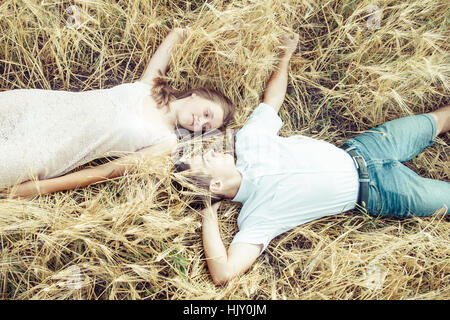 happy in love couple relaxing on wheat field Young couple lying on grass outdoor Stock Photo