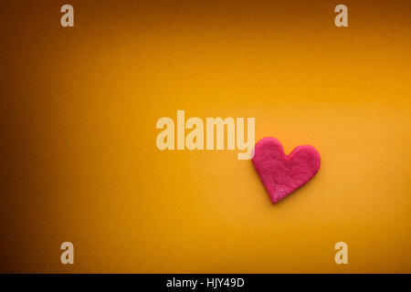 Red heart with small cracks on yellow background. Close up. Stock Photo