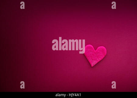 Red heart with small cracks on hot pink background. Close up. Stock Photo