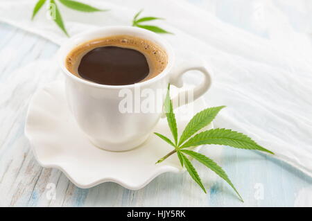 Hot coffee and marijuana leaves on a table Stock Photo