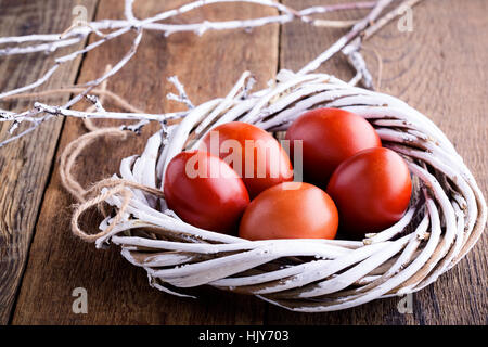 Easter painted red eggs in  white  willow tree wreath on wooden rustic table Stock Photo