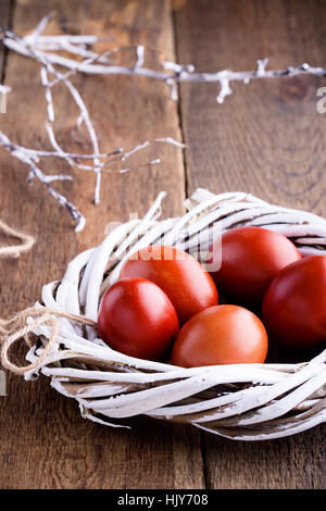 Easter painted red eggs in  white  willow tree wreath on wooden rustic table Stock Photo