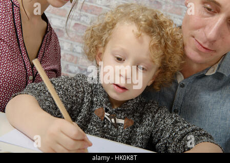 little blond curly boy drawing with his parents Stock Photo