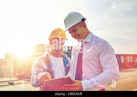 happy builders in hardhats with tablet pc outdoors Stock Photo
